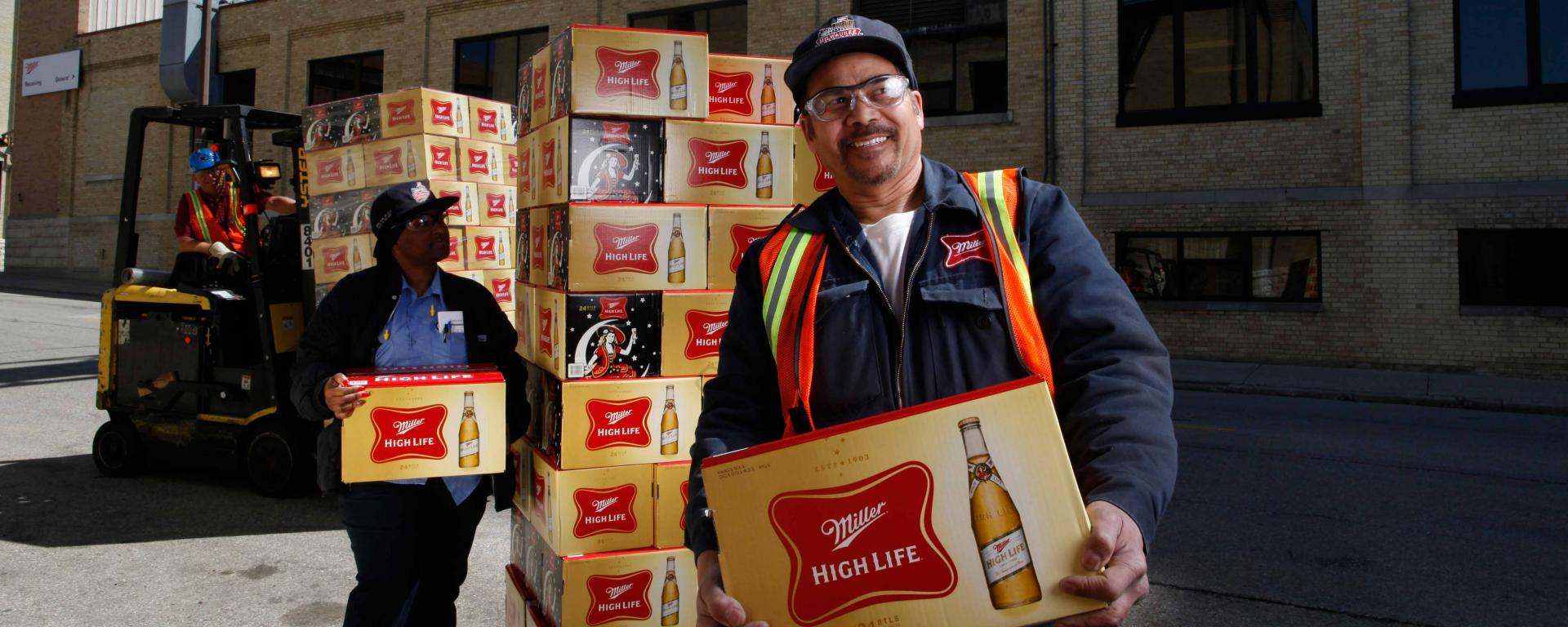 Employees holding Miller High life boxes
