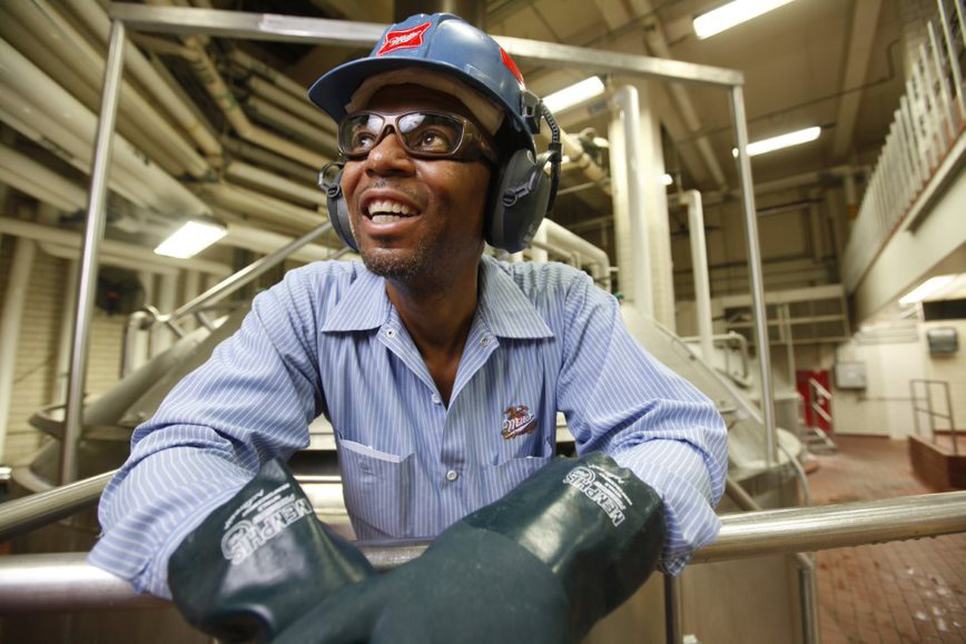 Man wearing protective gloves and goggles, smiling at work