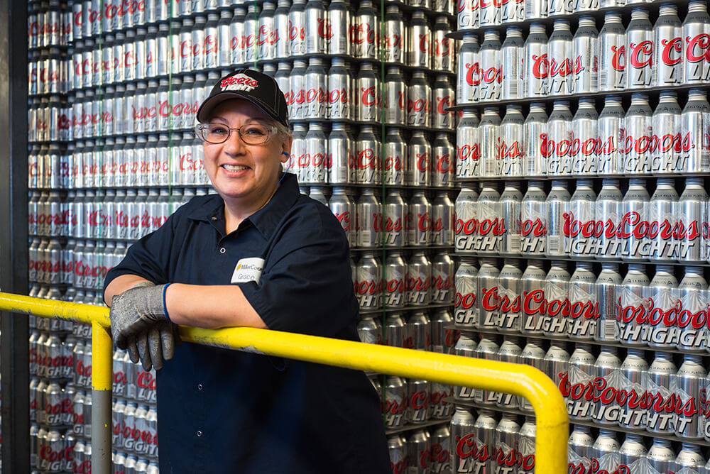 Employee standing in front of Coors cans