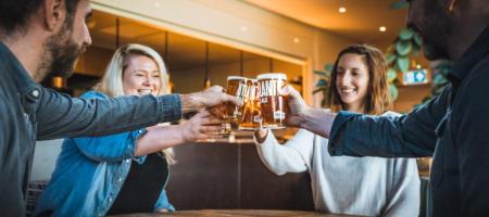 A group of friends joining glasses in a 'cheers!' motion.